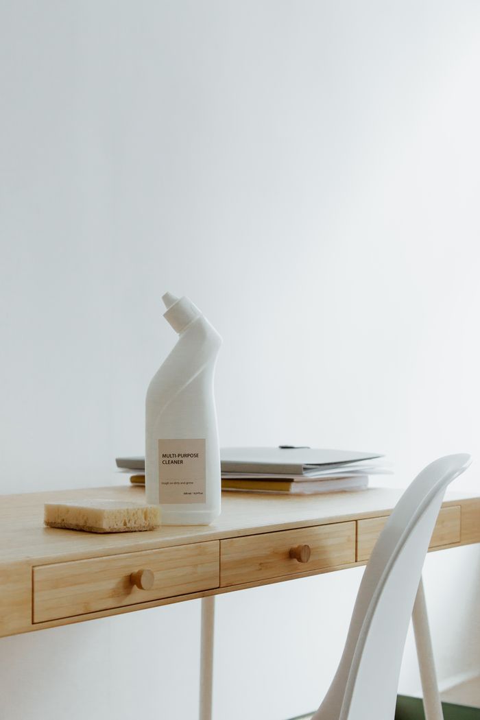 Un bureau à domicile propre et bien rangé avec une bouteille de nettoyant et une éponge, mettant l’accent sur la simplicité et la fonctionnalité.
